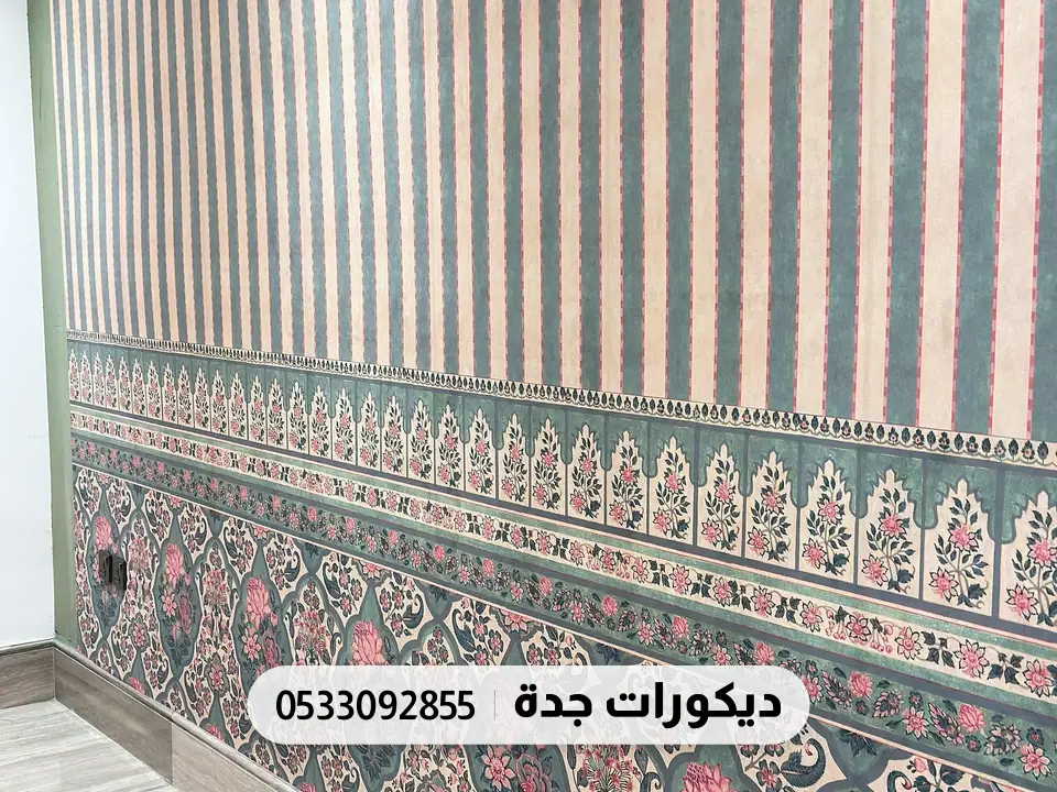 جدار بورق خطوط طولية زرقاء وبيج يحدّه من الأسفل إفريز زخارف ورود