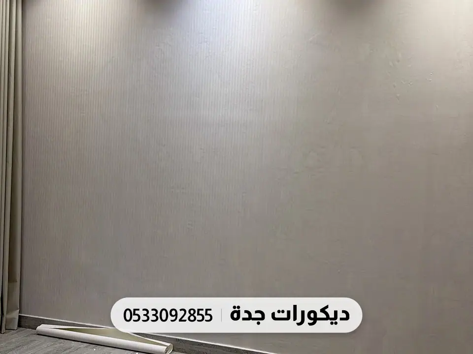 غرفة فارغة بجدار رمادي دافئ سادة وأرضية خشبية وإضاءة سقف